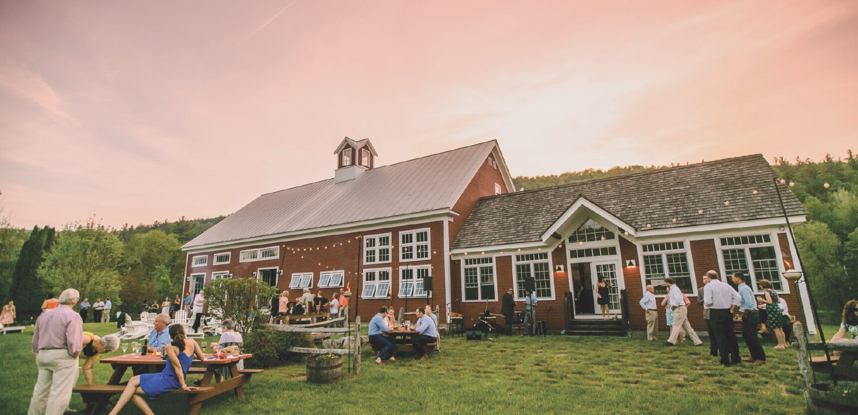 Riverside Farm's red barn glowing under a sunset sky